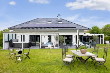 Moderner weißer Bungalow mit überdachter Terrasse und Garten